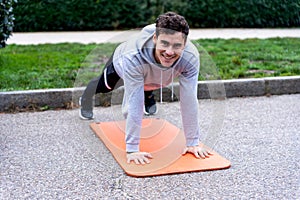 Smiling man doing plank exercise in park