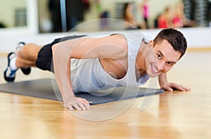 Smiling man doing push-ups in the gym