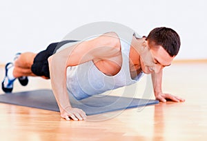 Smiling man doing push-ups in the gym