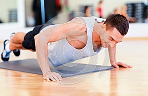 Smiling man doing push-ups in the gym