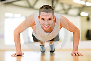 Smiling man doing push-ups in the gym