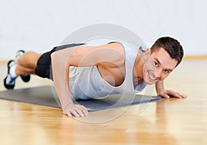 Smiling man doing push-ups in the gym
