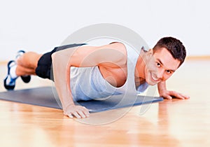 Smiling man doing push-ups in the gym