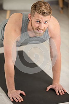 smiling man doing push-ups in gym or at home