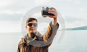 Smiling man doing self-portrait on coastline