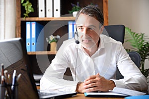 Smiling man doing video conference with headphones in an office