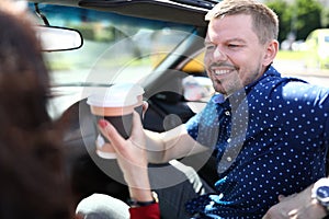 Smiling man drinks drinks with a woman in car.