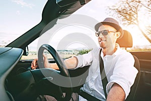 Smiling Man driving cabriolet car by province mountain road inside car view