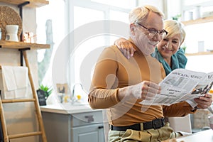 Smiling man engaging in reading while his spouse embracing him