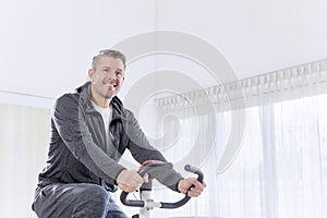 Smiling man exercising on a spin bike at home