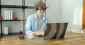 Smiling man with eyeglasses using laptop working at home