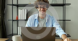 Smiling man with eyeglasses using laptop working at home