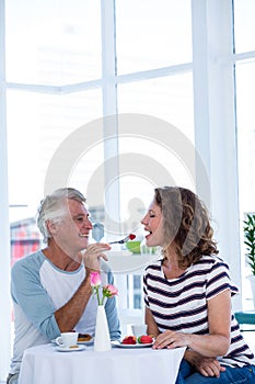 Smiling man feeding food to woman
