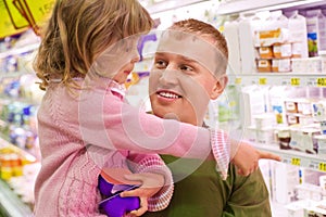 Smiling man with girl buy yogurt in supermarket