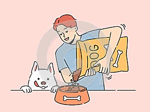 Smiling man give food from package to dog