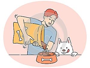 Smiling man give food from package to dog