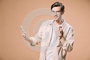 Smiling man in glasses holding smartphone and listening music in earphones isolated photo