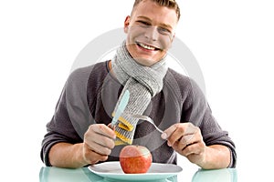 Smiling man going to eat apple with fork and knife