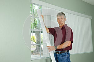Smiling man hanging vertical blinds window treatment