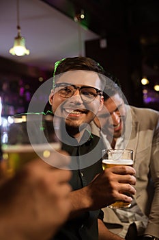 Smiling man having beer with his friends in a pub