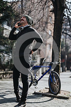 Smiling man with headphones using a vintage camera on a city street