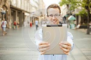 Smiling man hold tablet computer on urban street