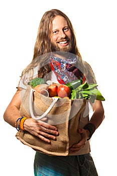 Smiling man holding a bag of fruit and vegetables.