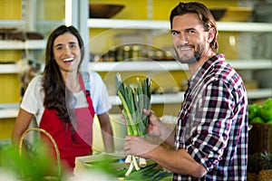 Smiling man holding a bunch of spring onions in the grocery store