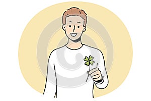 Smiling man holding clover with four leaves