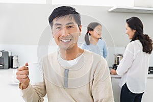 Smiling man holding coffee cup with family in background