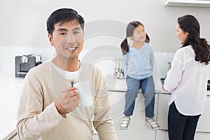 Smiling man holding coffee cup with family in background