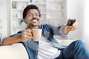 Smiling Man Holding Coffee Mug and TV Remote Control