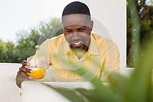 Smiling man holding juice glass while looking at laptop