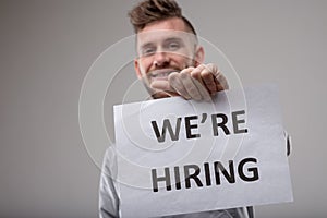 Smiling man holding up a sign We`re Hiring