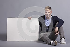 Smiling man holding white empty signboard.