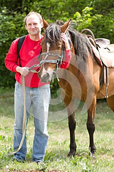 Smiling man with horse in the forest