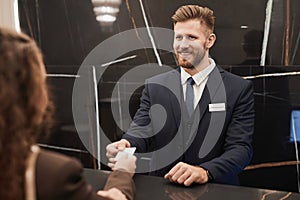 Smiling Man at Hotel Reception Desk Welcoming Guest