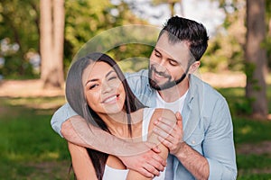 Smiling man hugging happy wife outdoors