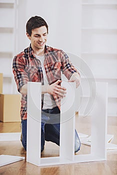 Smiling Man Installing Furniture in New Home.