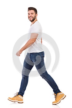 Smiling Man In Jeans And White T-shirt Is Walking Side View