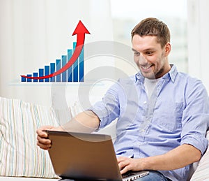 Smiling man with laptop and growth chart at home