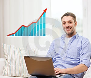 Smiling man with laptop and growth chart at home
