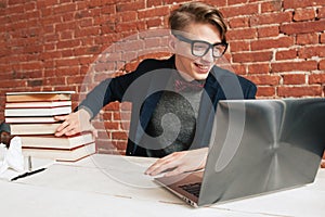 Smiling man with laptop move away pile of books