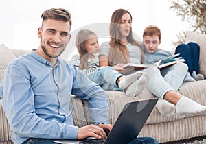 Smiling man with laptop sitting in his living room