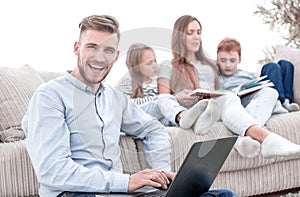 smiling man with laptop sitting in his living room