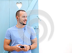 Smiling man listening to music on mobile phone with earphones