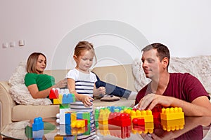 Smiling man and little girl playing with cubes together at home