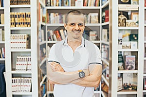 Smiling man looking in camera with bookshelfs behind in the library
