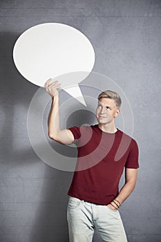 Smiling man looking at empty speech bubble.