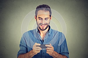 Smiling man looking at his smart phone while text messaging or watching video